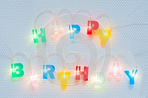 Happy birthday inscription. Multicolored glowing letters on white glossy background. Led volumetric lettering.