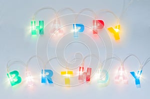 Happy birthday inscription. Multicolored glowing letters on white matte background. Led volumetric lettering.