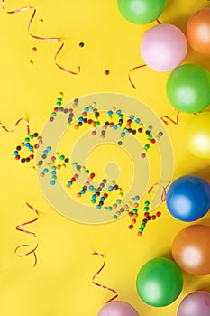 Happy birthday letters from candies. Birthday background. Colorful balloons and candies on yellow table