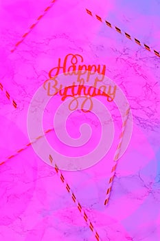 Happy birthday letters with festive straws on marble background with neon pink creative toning. Futuristic party and
