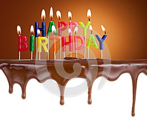 Happy birthday lit candles on chocolate cake