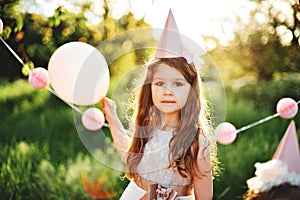 Happy birthday little girl with pink decor in beautiful garden.