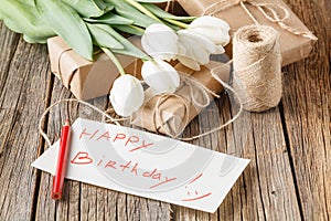 Happy birthday mesage with flowers on rustic table with flowers photo