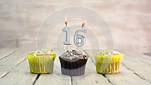 Happy birthday muffins with candles with the number 16. Card copy space with pies for congratulations.