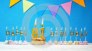Happy birthday from number 81 candle letters on a blue background with white polka dot copy space. Happy birthday cupcake
