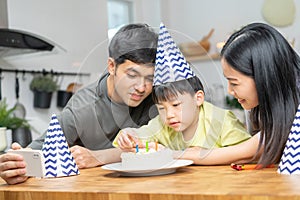 Happy birthday party in family, asian young parent father, mother and little cute boy or child celebrating, using smartphone
