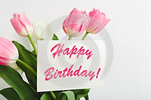 Happy Birthday text on gift card in flower bouquet. Beautiful bouquet of fresh flowers tulips with greeting card Happy Birthday on
