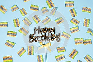 Happy birthday text with knot and jelly candy isolated on blue background