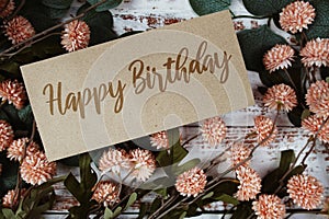 Happy Birthday text message on paper card with flowers border frame on wooden background