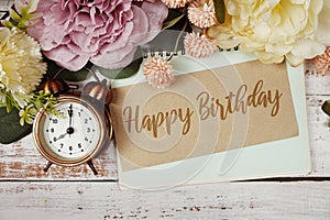 Happy Birthday text message on paper card with flowers border frame on wooden background