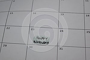 Happy Birthday text on monthly Calendar and marked 23th isolated on office desk photo