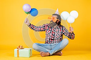 happy birthday to you. bearded mature man celebrate birthday party. cheerful man in bday hat hold holiday balloons