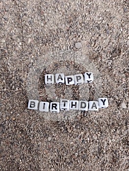 Happy birthday words written in sand at the beach