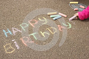 Happy birthday written in colored crayons on the sidewalk