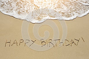 Happy birthday written on sand beach