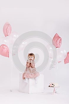 happy birthday 2 years old little girl in pink dress. white cake with candles and roses. Birthday decorations with white