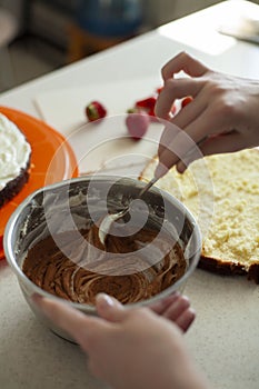 Happy birthday. A young woman is preparing cream for a cake. Festive cake decoration.