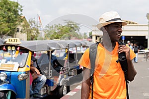 Happy black African tourist man in Bangkok with tuk tuk taxis