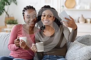 Happy black besties taking selfie on smartphone together at home