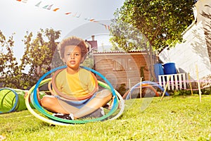 Happy black boy sit with hula rings on grass