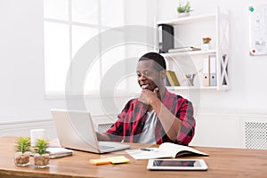 Happy black businessman in casual office, work with laptop