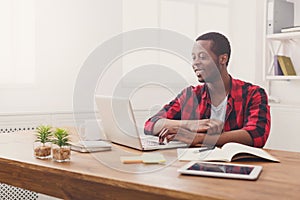 Happy black businessman in casual office, work with laptop