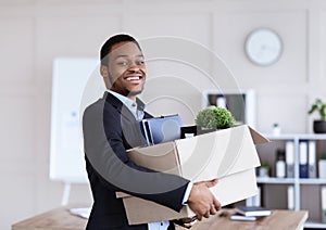 Happy black businessman moving office with box and his belongings