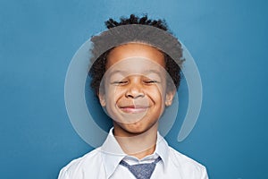 Happy black child boy maks a wish on blue background photo