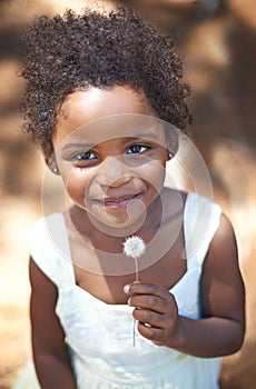 Happy, black child and portrait in nature, flower and summer holiday with sunshine in forest. Young, african toddler and