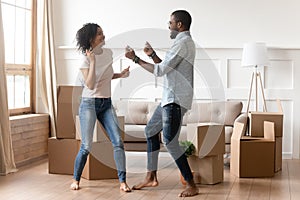 Happy black couple dancing in living room on moving day