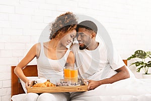 Happy black couple enjoying breakfast in bed