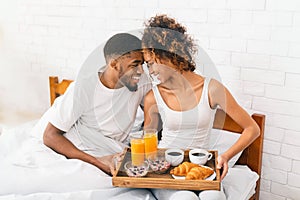 Happy black couple enjoying breakfast in bed