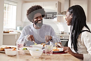 Happy black couple enjoying eating their Sunday dinner together at home, close up