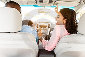 Happy black couple enjoying music driving car