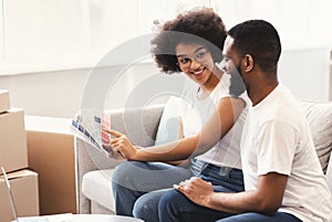 Happy Black Couple Planning Renovation After Moving House Sitting Indoor