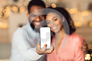 Happy black couple showing phone with blank screen, mockup