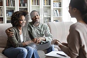 Happy black couple sitting in counselor office, successful marital therapy