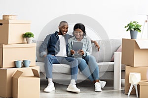 Happy Black Couple Using Digital Tablet Together After Moving To New Home