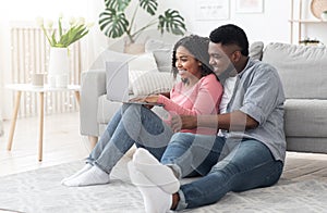 Happy Black Couple Using Laptop At Home For Online Shopping, Ordering Goods
