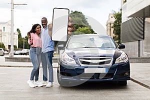 Happy black couple using showing smartphone with empty screen