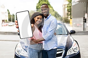 Happy black couple using showing smartphone with empty screen