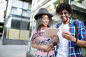 Happy black couple watching media in a digital table outdoor