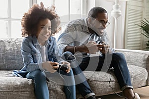 Happy Black dad and kid playing online computer video game