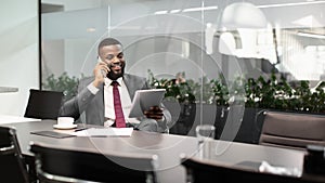 Happy black entrepreneur using digital tablet, talking on phone