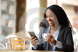 Happy black executive drinking and using phone