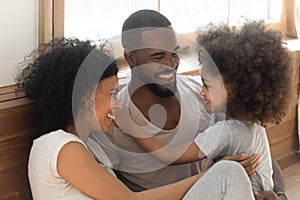 Happy black family bonding laughing sit on bedroom floor