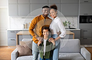 Happy black family with child smiling together in the kitchen