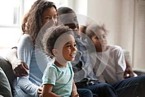 Happy black family with children sitting on couch watching tv