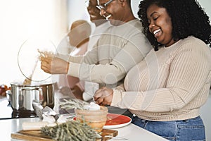 Happy black family cooking inside kitchen at home - Main focus on daughter face