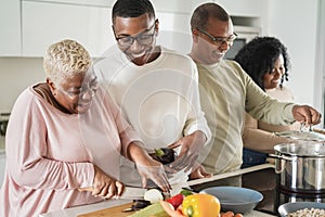 Happy black family cooking vegan food inside kitchen at home - Focus on son face